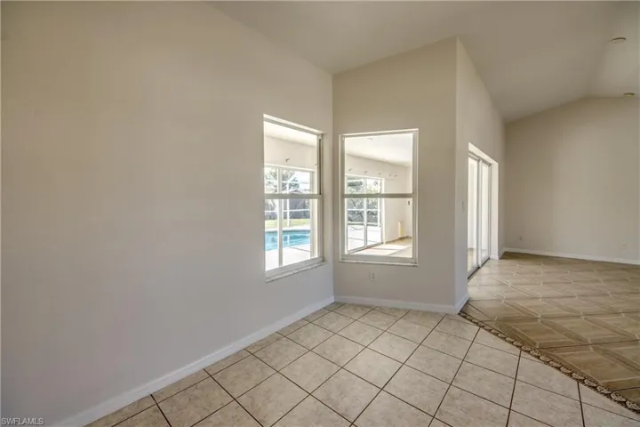 Empty room featuring light tile patterned floors and vaulted ceiling