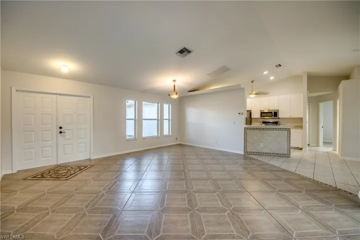 Unfurnished living room featuring lofted ceiling and baseboards