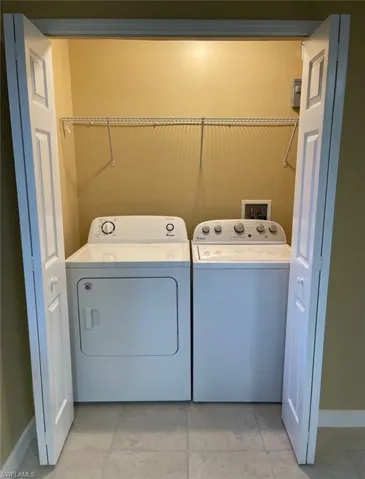 Laundry area featuring light tile patterned flooring and washer and clothes dryer