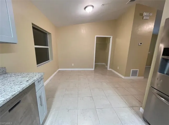 Unfurnished dining area featuring vaulted ceiling and light tile patterned floors