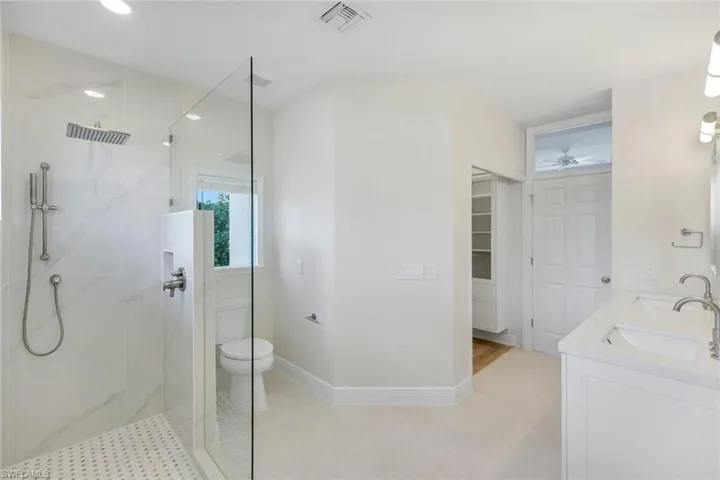 Primary Bathroom featuring a marble finish shower and double vanity