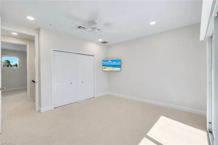 Unfurnished bedroom featuring light colored carpet, a ceiling fan, a closet, and recessed lighting