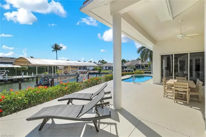 View of patio / terrace featuring a ceiling fan, a water view, an outdoor pool, a dock, and a residential view