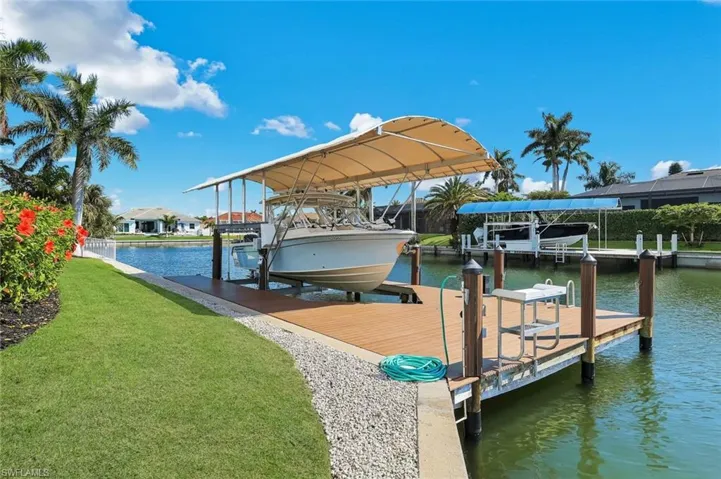 Dock area with a water view, boat lift, and a yard