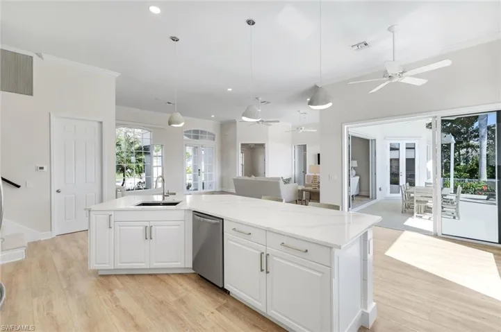 Kitchen featuring french doors, white cabinets, a kitchen island with sink, a ceiling fan, and light wood-style flooring