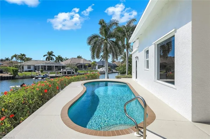 Swimming pool with a residential view, a patio area, and a water view