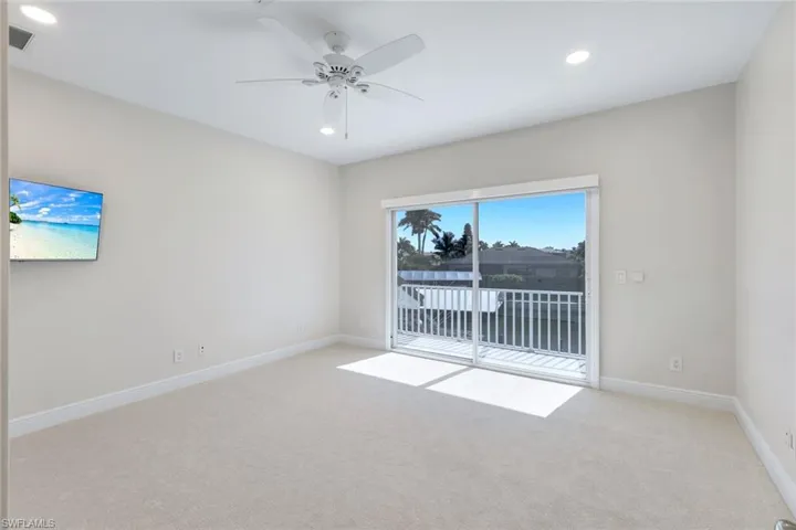 Unfurnished room with light colored carpet, a ceiling fan, and recessed lighting as well as access to the balcony located upstairs