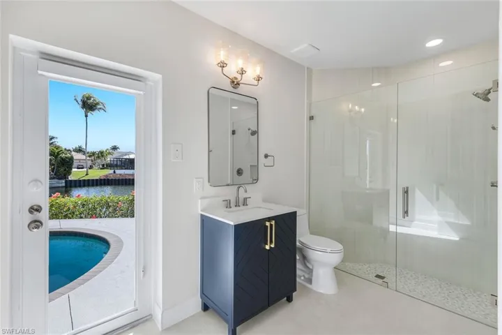 Bathroom featuring vanity, a shower stall, and a water view, with pool access