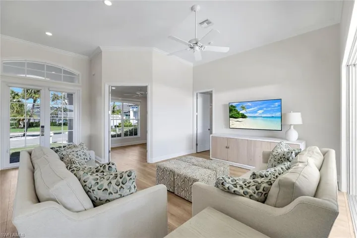 Living area with ornamental molding, light wood-type flooring, recessed lighting, and a ceiling fan