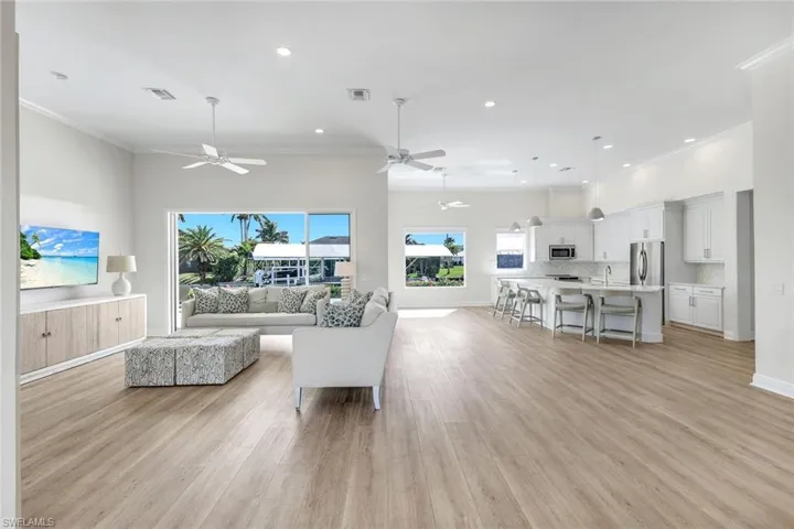 Living area with ornamental molding, light wood-style flooring, recessed lighting, and ceiling fan
