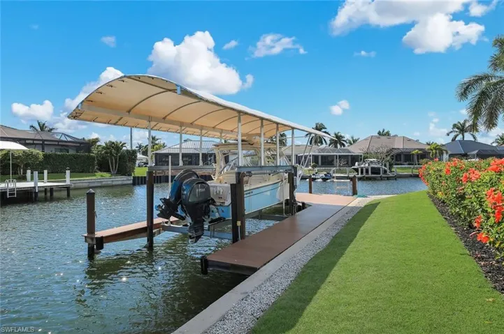 Dock with boat lift, a water view, and a lawn