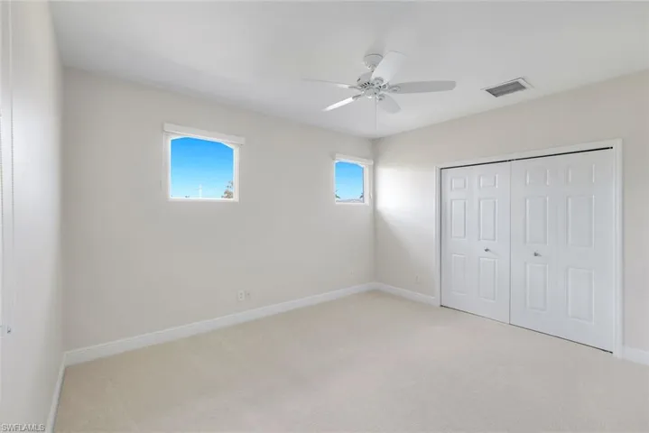 Unfurnished bedroom featuring light colored carpet, multiple windows, a closet, and ceiling fan, located upstairs