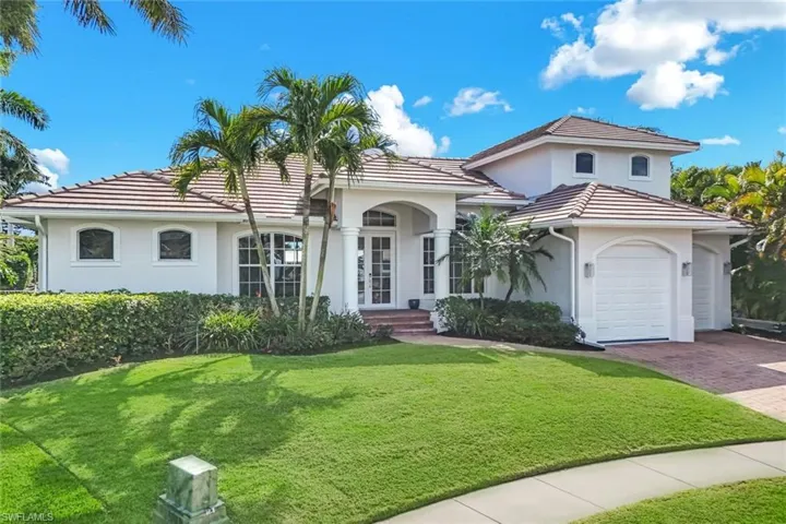 Mediterranean / spanish-style home with stucco siding, a front lawn, an attached garage, and decorative driveway