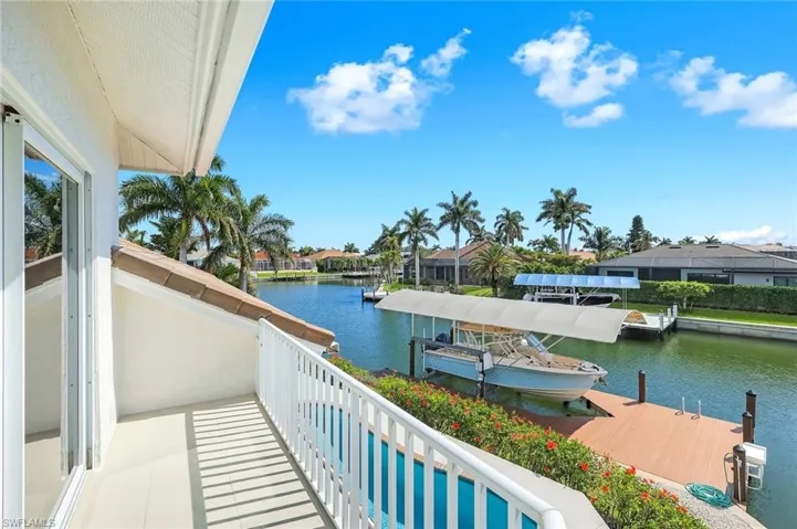 Balcony with a water view, a dock, a residential view, boat lift, and view of pool