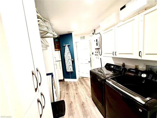Laundry area featuring light wood finished floors, cabinet space, and separate washer and dryer