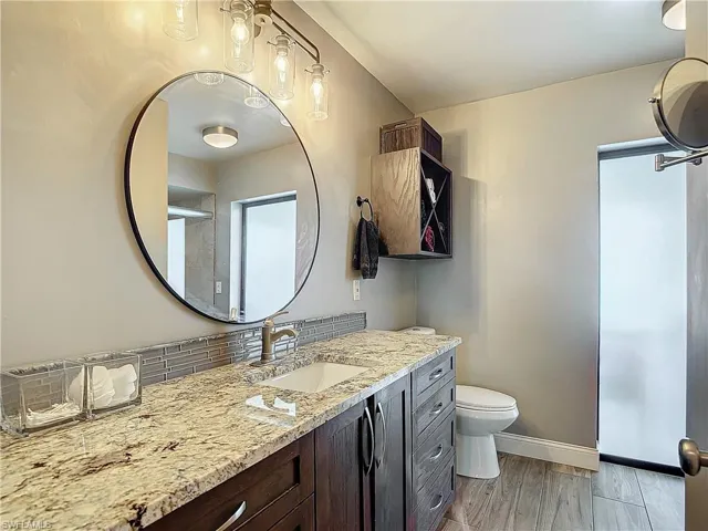 Full bath with vanity, light wood-type flooring, and decorative backsplash