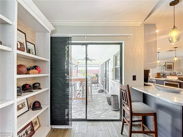 Doorway featuring wood finished floors, crown molding, and a ceiling fan