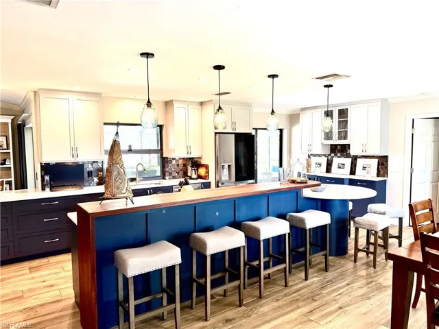 Kitchen featuring backsplash, a kitchen bar, ornamental molding, a center island, and decorative light fixtures