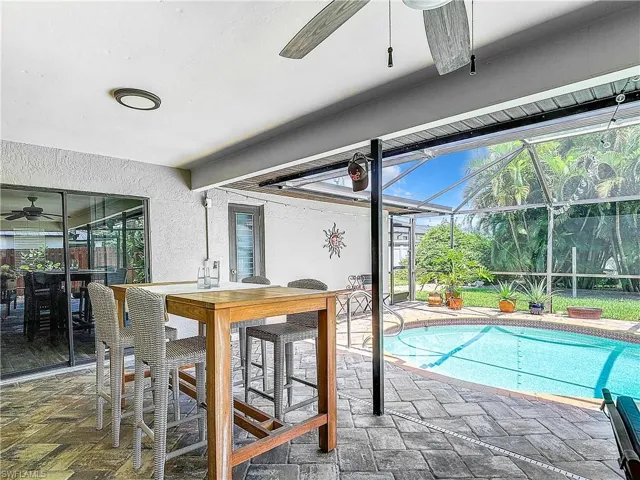 Outdoor pool featuring a patio, ceiling fan, a lanai, a sunroom, and outdoor dining space