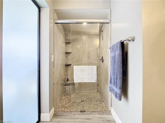 Full bath featuring a shower stall and baseboards