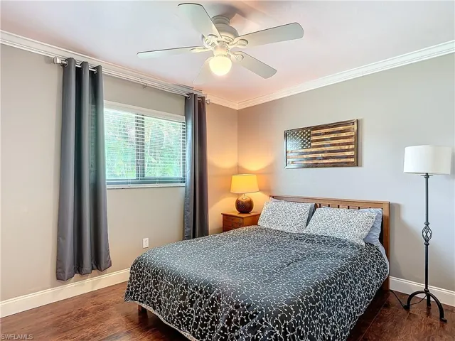 Bedroom with ornamental molding, dark wood-style floors, and ceiling fan