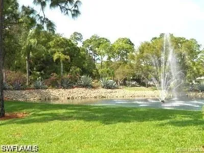 Water feature with an active fountain, surrounded by a rock-lined bank and tropical landscaping