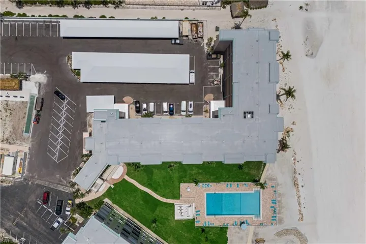 From above, the rooftop reveals the full property—lush grounds, the sparkling community pool, and pathways all leading toward the beach beyond.