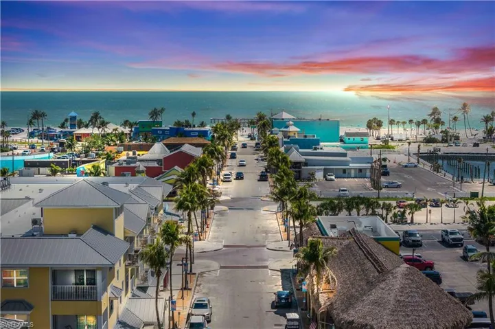 From above, the streets of Fort Myers Beach unfold in a charming grid, lined with tropical trees and colorful homes, all leading directly to the inviting sandy shoreline and shimmering Gulf beyond.