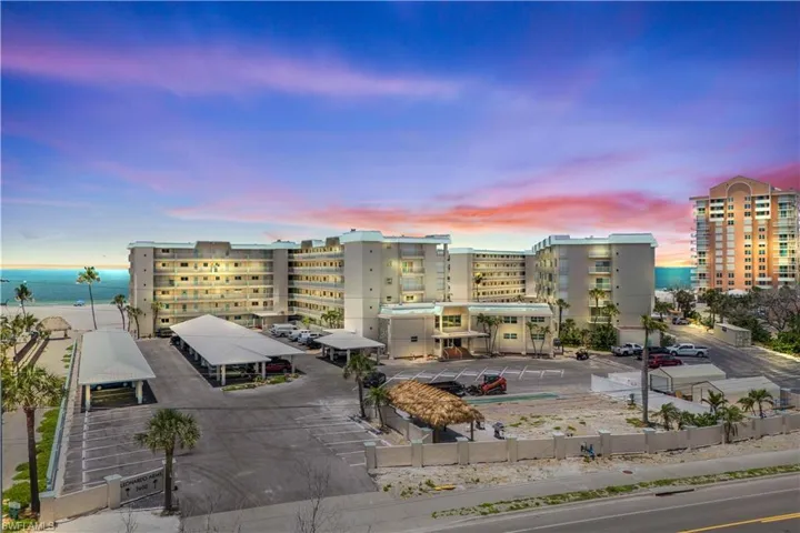 At dusk, the building’s exterior is bathed in golden sunset hues, while soft lighting creates a welcoming glow—offering a serene and elegant beachfront atmosphere.