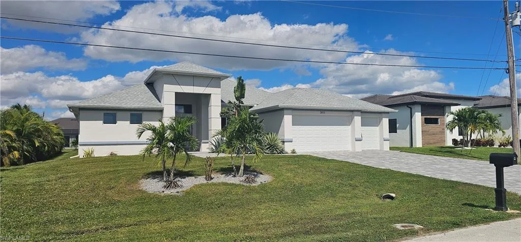View of front of home with stucco siding, a garage, decorative driveway, and a front yard