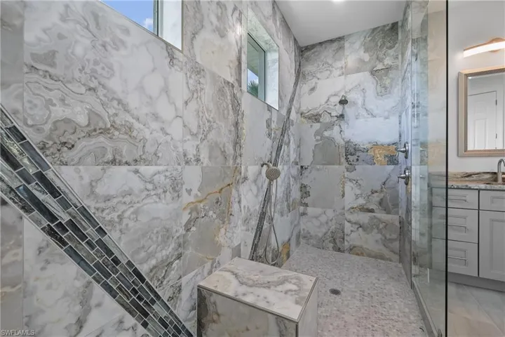 Bathroom featuring a marble finish shower and vanity