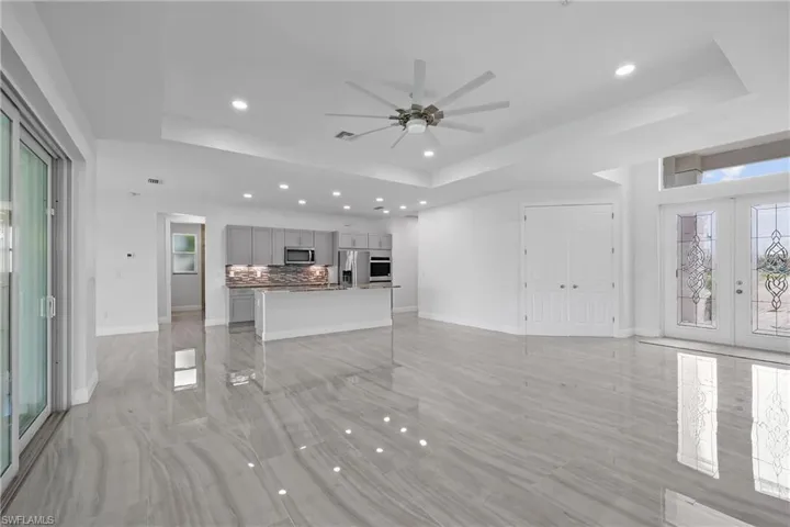 Unfurnished living room with plenty of natural light, a tray ceiling, recessed lighting, french doors, and ceiling fan