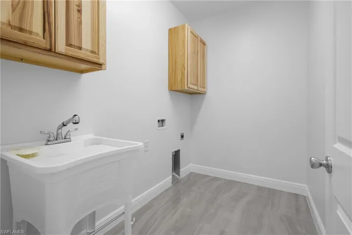Washroom featuring electric dryer hookup, cabinet space, and washer hookup