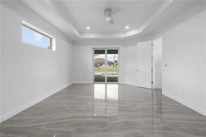 Unfurnished room with healthy amount of natural light, a tray ceiling, recessed lighting, and ceiling fan