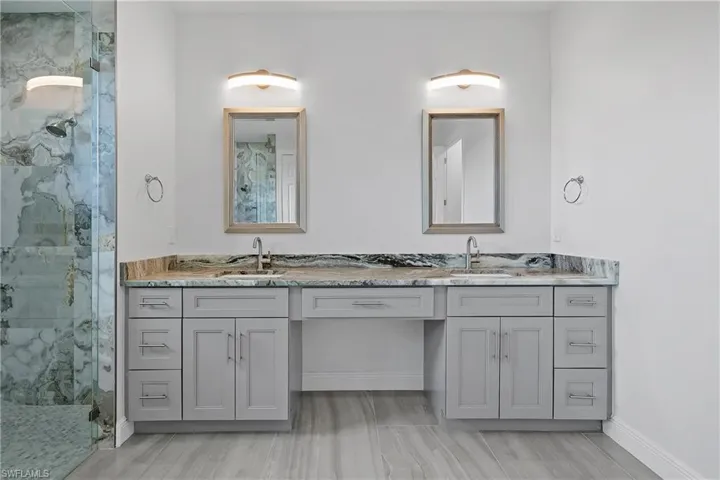 Full bathroom featuring double vanity and a marble finish shower
