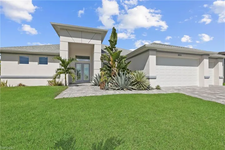 View of front of home with a front lawn, stucco siding, decorative driveway, and an attached garage
