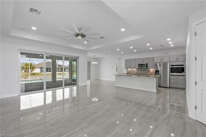 Unfurnished living room featuring a raised ceiling, recessed lighting, and ceiling fan