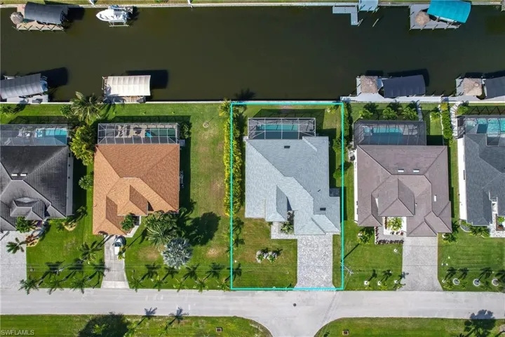 Aerial perspective of suburban area featuring property boundaries highlighted and a nearby body of water