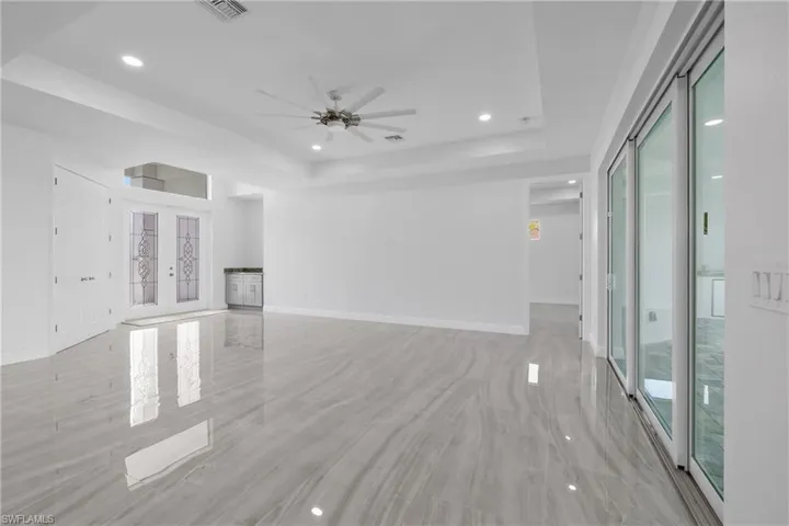 Unfurnished living room with a tray ceiling, recessed lighting, french doors, plenty of natural light, and ceiling fan