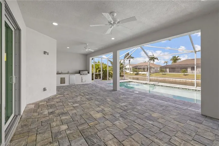 View of patio / terrace featuring a sunroom, a ceiling fan, a lanai, a residential view, and an outdoor pool