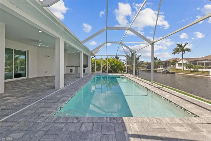 Swimming pool with a water view, a sunroom, a patio, ceiling fan, and glass enclosure