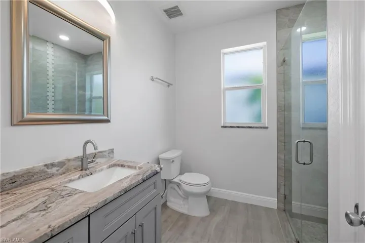Full bathroom with a stall shower, vanity, and light wood-type flooring