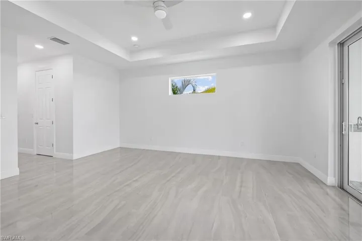 Unfurnished room with a tray ceiling, recessed lighting, light wood-style flooring, and a ceiling fan