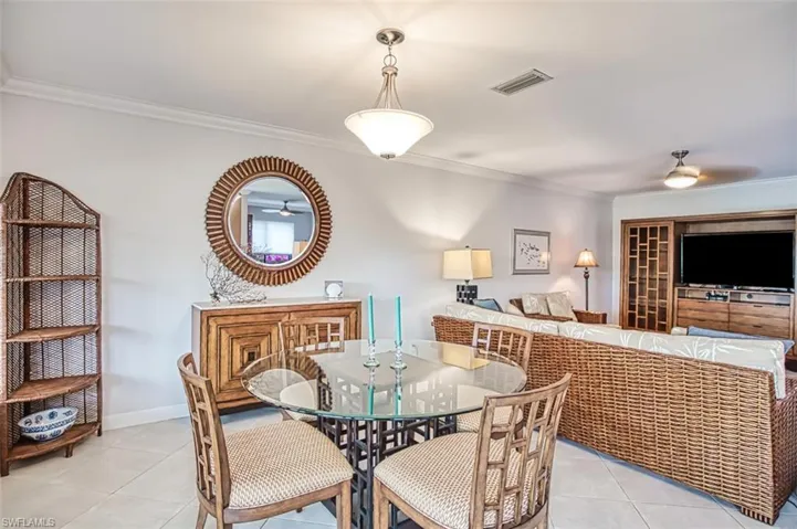 Dining area with light tile patterned floors, ornamental molding, and ceiling fan