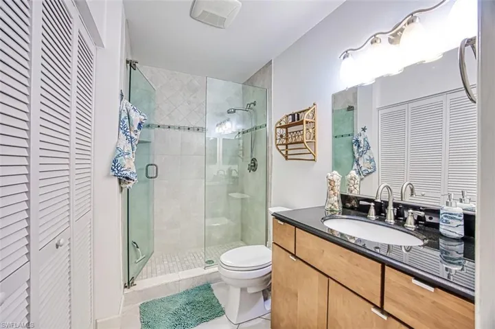 Bathroom with tile patterned flooring, vanity, walk in Tile shower, and toilet