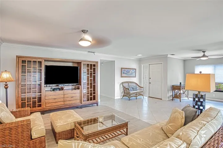 Living room with crown molding, light tile patterned floors, and ceiling fan