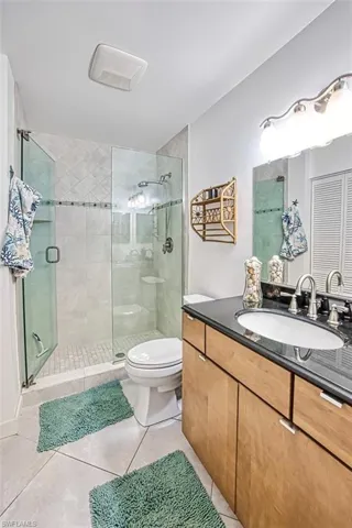 Bathroom with tile patterned flooring, toilet, vanity, and a shower with glass shower door