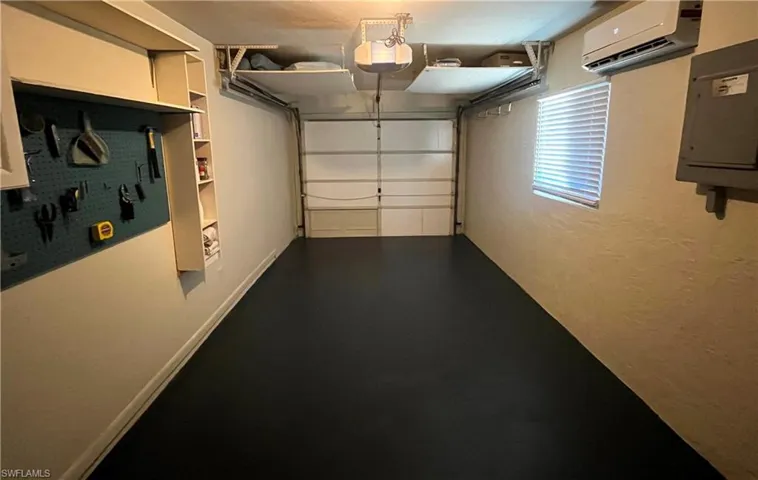 Garage with a garage door opener, an AC wall unit, and electric panel