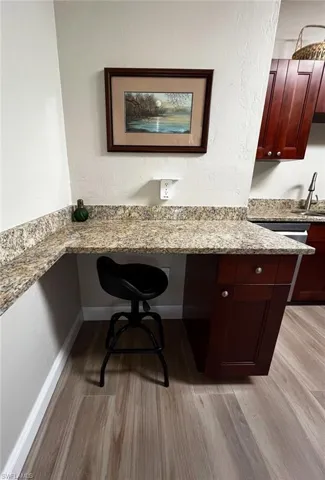Home office featuring built in desk, light wood-style floors, a sink, and baseboards