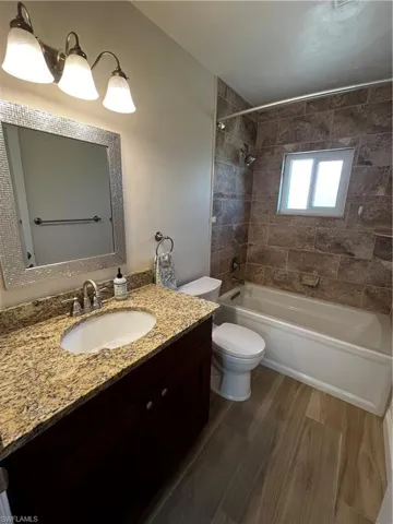 Bathroom featuring bathing tub / shower combination, toilet, vanity, and wood finished floors